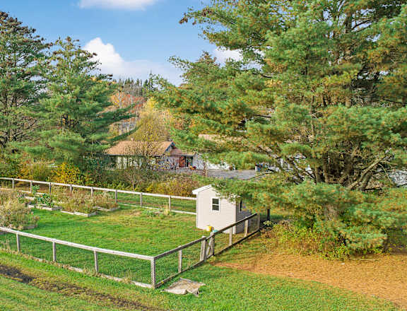 a farm with a fence and a small white house in a field