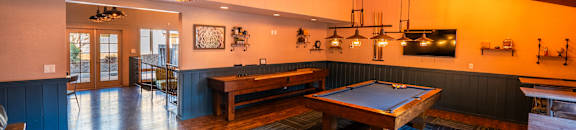 A room with a pool table and a bar area.