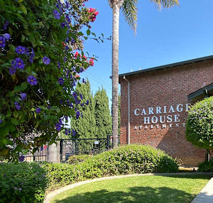 a sidewalk in front of a building with a sign that reads carriage house