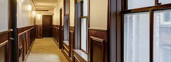 A long hallway with wood trim and windows on the side.