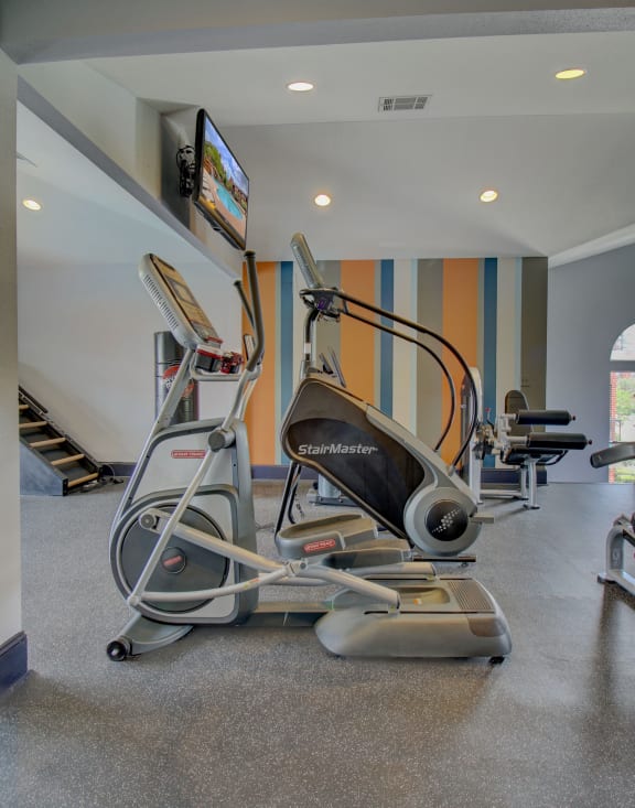 a room filled with cardio equipment and a flat screen tv