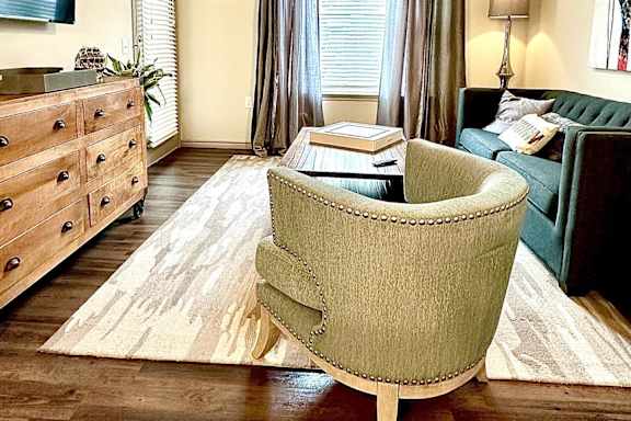 A living room with a green chair and a rug.