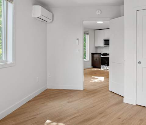 a renovated living room with white walls and wood floors