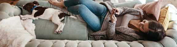 a woman laying on a couch with a dog at Littlebrook Apartments, Hudson, Massachusetts