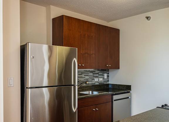 A kitchen with a stainless steel refrigerator and granite countertops.