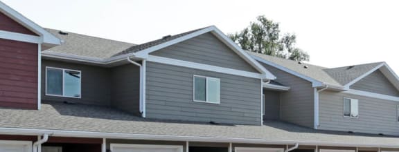 a row of houses with garages and cars in a parking lot