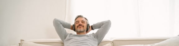 man on couch at home with dog listening to music at Avenue Two Apartments, Redwood City, CA