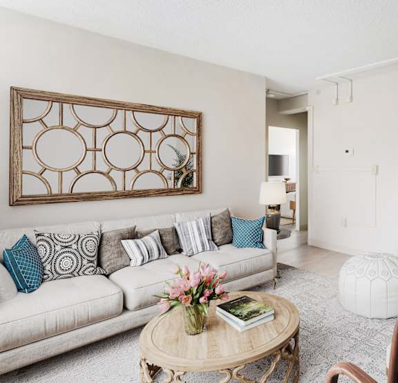 A living room with a couch, a chair, a coffee table, and a potted plant.