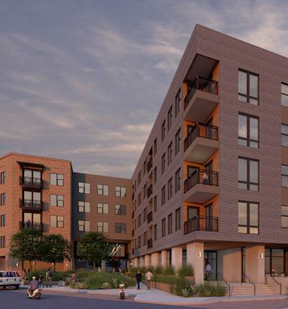 A modern apartment complex with cars parked in front.