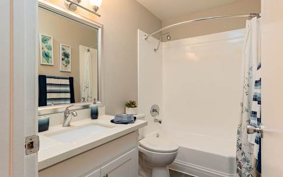 A white bathroom with a toilet, sink, and shower at Nola 624 Apartments, West Covina, 91790
