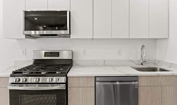A modern kitchen with a refrigerator, oven, and a view of the outdoors through the door.