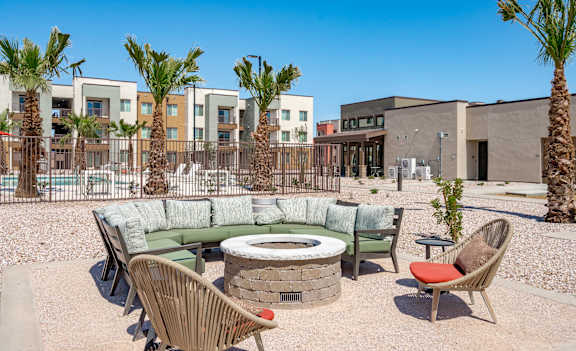 A patio area with a fire pit, chairs, and a couch.