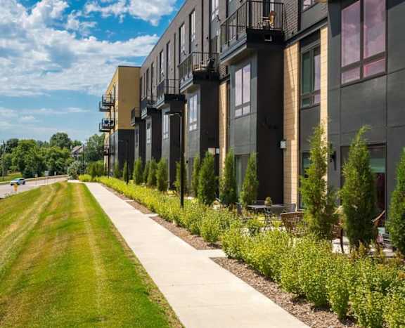 Exterior of Aspire at CityPlace with paved sidewalk, grass, and lush landscaping