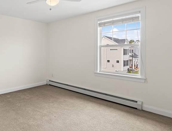 an empty bedroom with a ceiling fan and a window