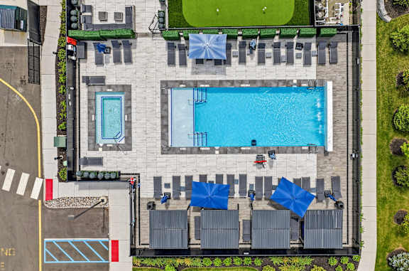 An aerial view of a pool with a green lawn and a building.