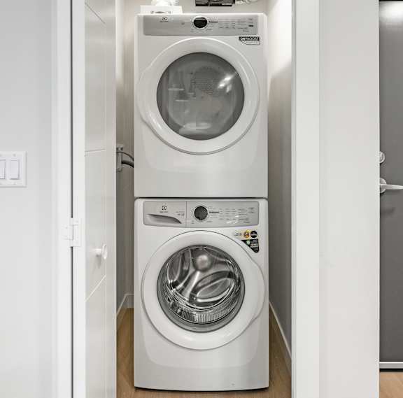 A white washing machine and dryer in a small laundry room. at Skyway Apartments, Alberta, T3B 5V6