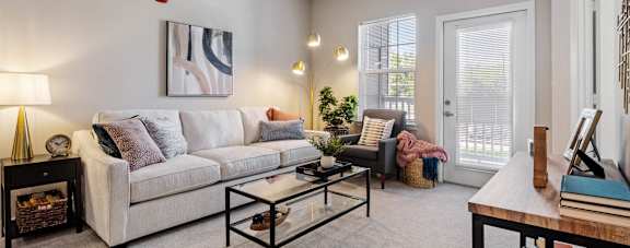 A living room with a white couch, a coffee table, and a painting on the wall at Aventura at Wentzville I & II Apartments, Missouri, 63385