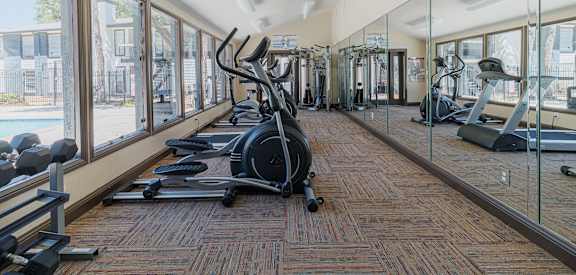 a gym with cardio equipment and windows at the district at highland village apartments