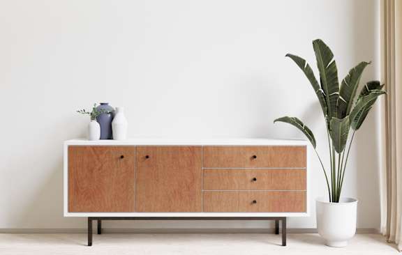 A white cabinet with a plant beside it.
