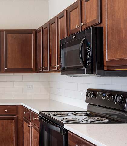 a kitchen with dark wood cabinets and white countertops at The Fairways at Star Ranch, Texas, 78634