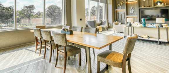 a dining room with a wooden table and chairs and large windows