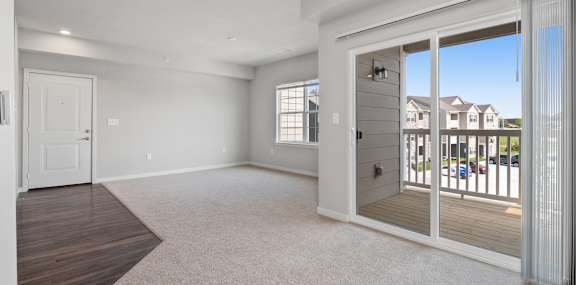 A spacious living room with a sliding glass door leading to a balcony.