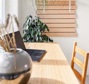 Apartment workspace with a wooden table, laptop, and vase representing comfortable living at Willow Creek Apartments.