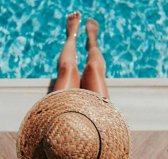 Woman sitting with legs in pool at AVIA Apartments On Alpha, Texas, 75240