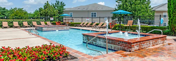A pool area with a hot tub and lounge chairs.