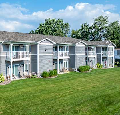 the view of an apartment building with a green lawn