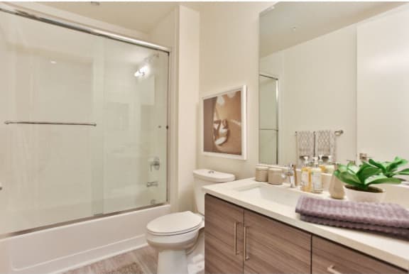 Old Town Scottsdale Apartments - Bathroom With a Quartz Vanity, Designer Fixtures, Modern Custom-Wood Cabinetry, Wood-Style Flooring, And A Shower With Tub.