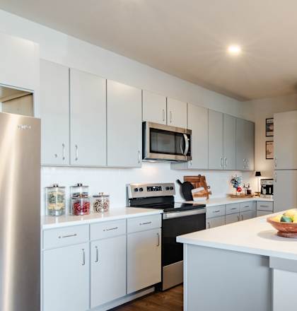 a kitchen with white cabinets and a white island with two stools at Parkside at Littleton Village, Littleton, 80122