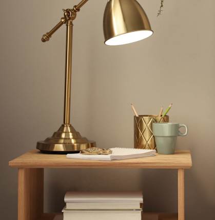 A bedside table with a lamp, a cup, and a plant.