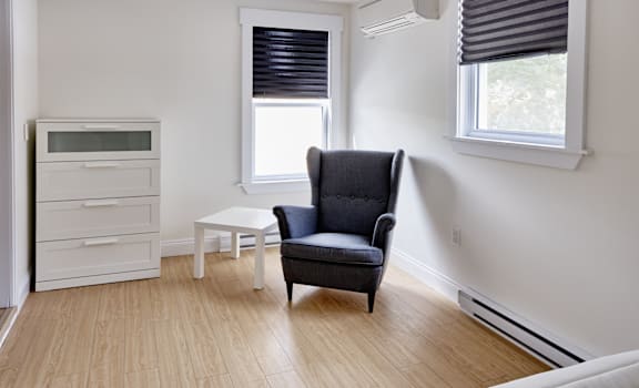 A black chair sits in a white room with a white table and a white microwave.