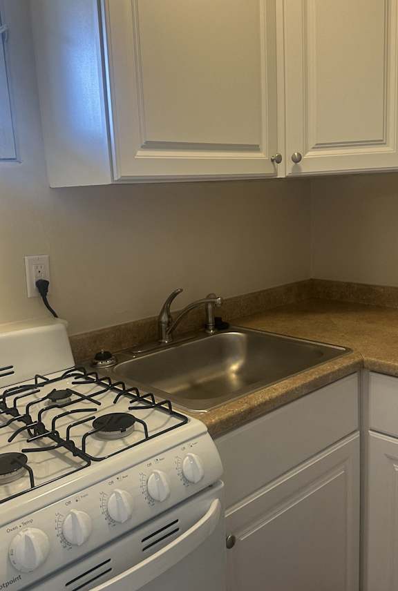 a kitchen and living room with white cabinets and wood floors