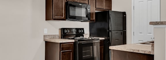 A kitchen area with a microwave, oven, and refrigerator.