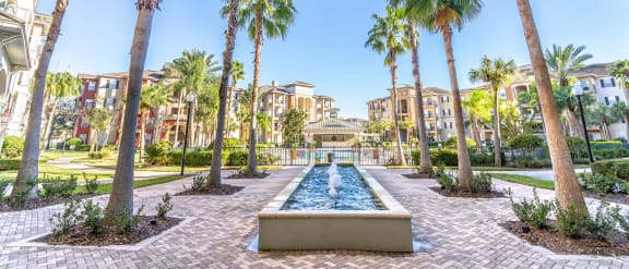 a fountain surrounded by palm trees in the middle of a resort