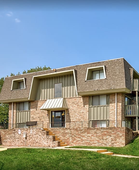 an apartment building with a grassy yard and a blue sky