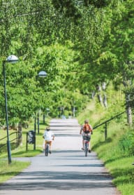 two people riding bikes down a path in a park at Mountain Breeze Apts, Pomona, CA