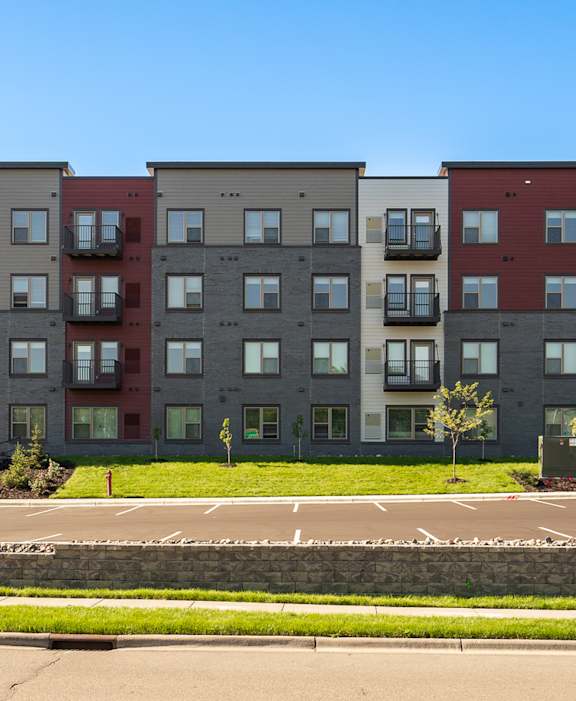 Apartment building with a parking lot in front.
