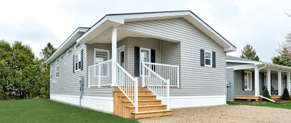 A house with a grey siding and a white porch.