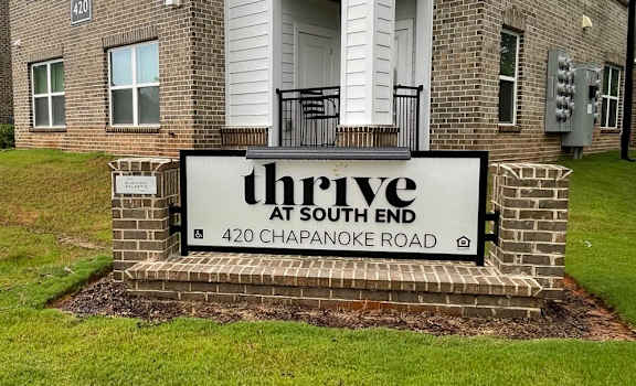 A sign for Thrive at South End is in front of a brick building.