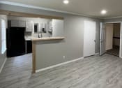 Thumbnail 12 of 27 - an empty living room with a kitchen in the background at The Lodge Apartments, Tulsa, 74129