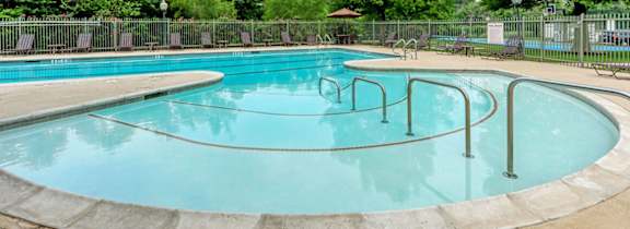 A round swimming pool surrounded by a fence and trees.