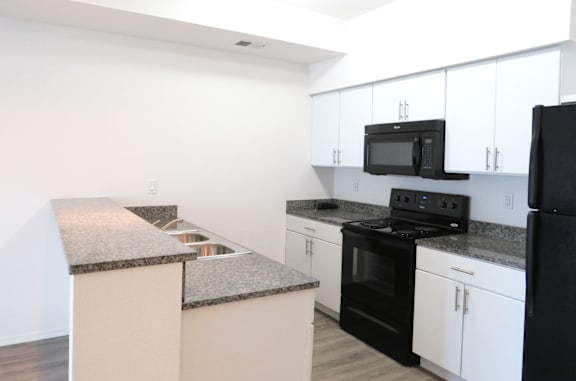 A kitchen with black appliances and white cabinets.
