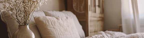 a bedroom with a bed and a vase with white flowers