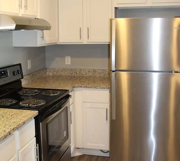 A kitchen with a stainless steel refrigerator, oven, and cabinets.