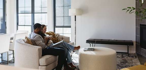 Two people sitting on a couch in a living room.