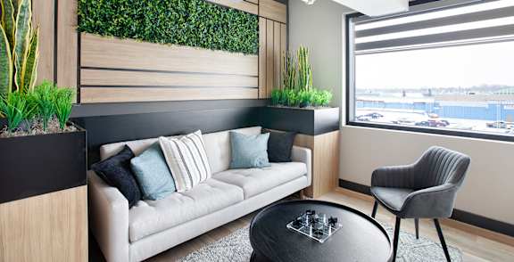 A living wall with plants on the side of a room with a couch and chair.