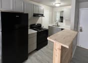 Thumbnail 15 of 27 - a kitchen with a black refrigerator freezer next to a stove top oven at The Lodge Apartments, Oklahoma, 74129